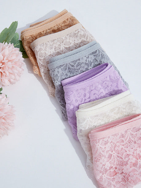 Colorful collection of sexy lace seamless mesh thong panties arranged neatly with flowers in the background.